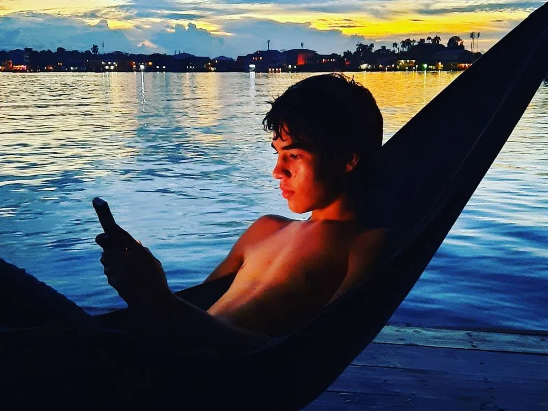 Relaxing in a hammock beside the water at sunset