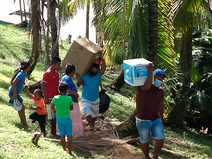 Local partners carrying outreach boxes through an island community